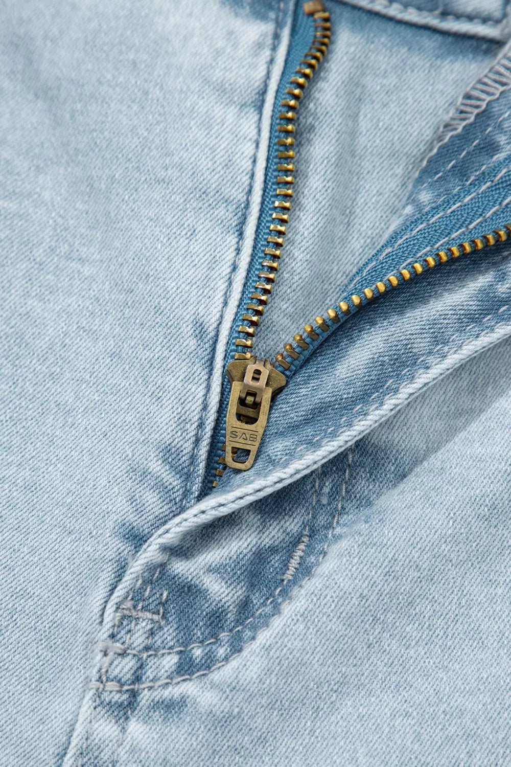 Zipper and contrast stitching detail on light wash jeans in light blue denim