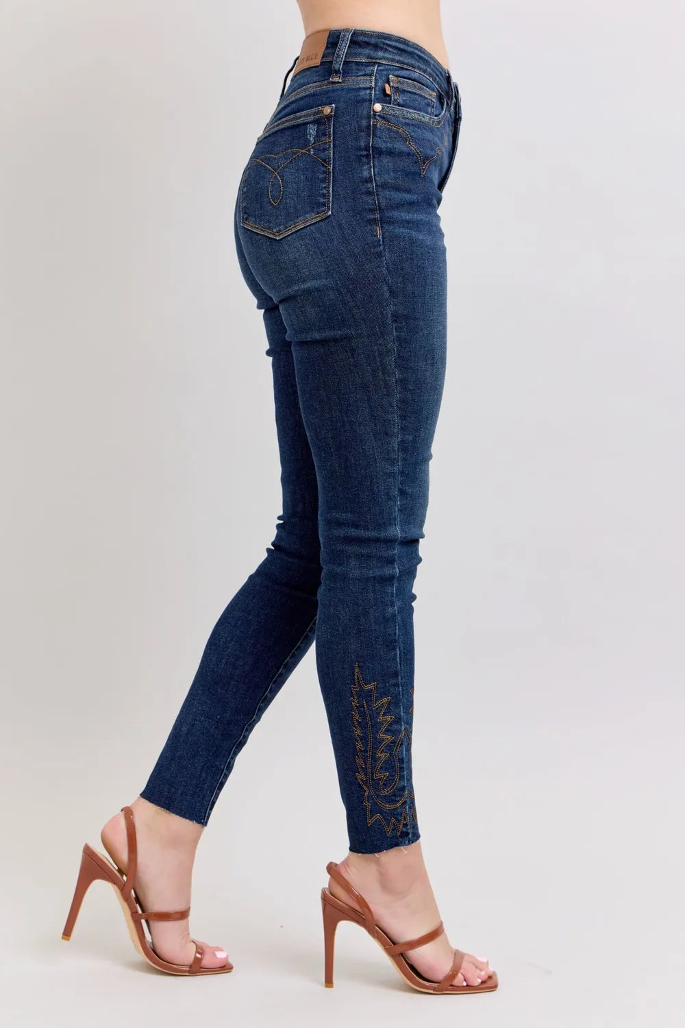 Dark blue high-rise skinny jeans, side/back view with embroidered lower leg