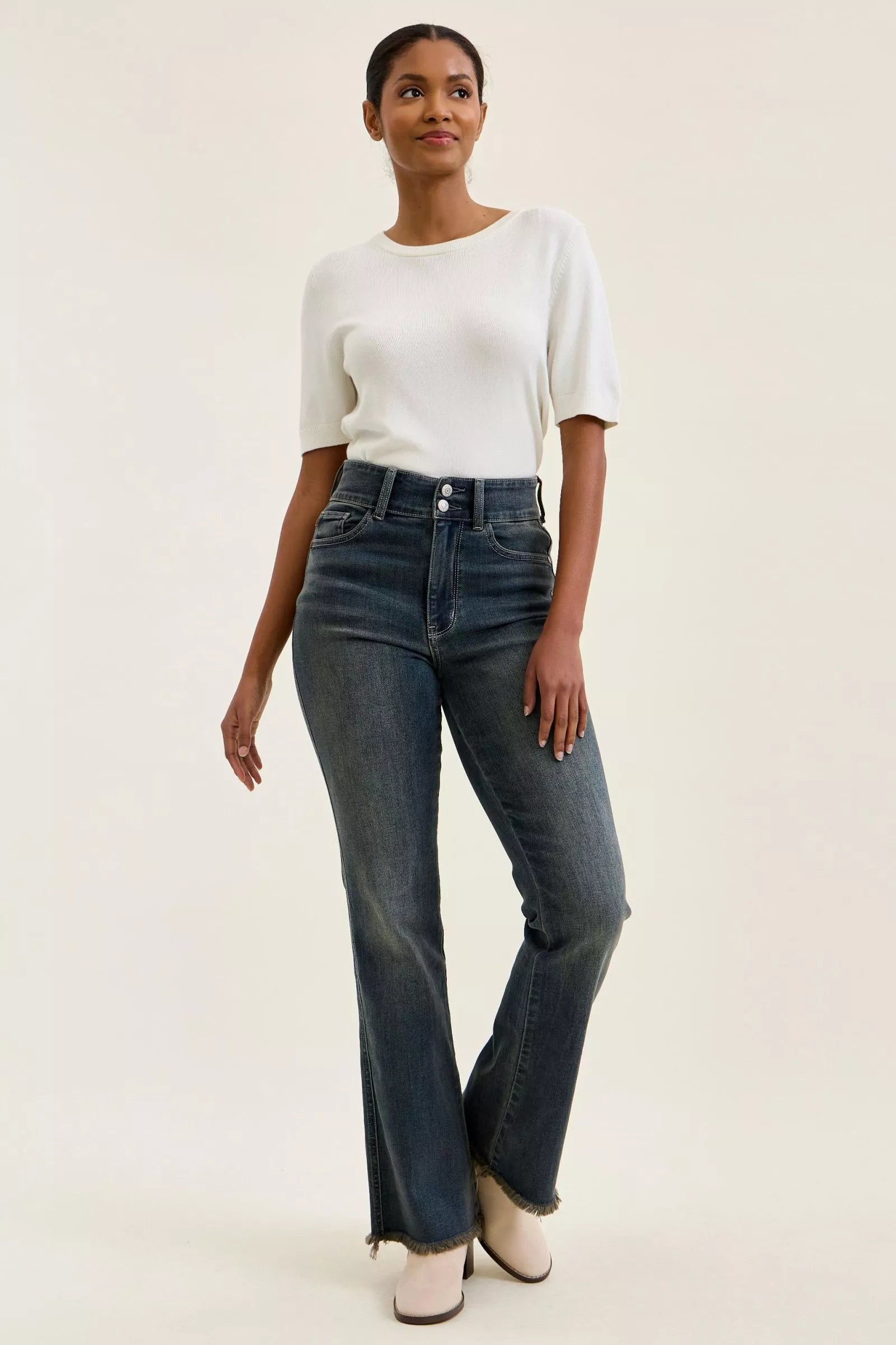 High-waist medium-wash jeans with double-button closure and frayed ankle hem