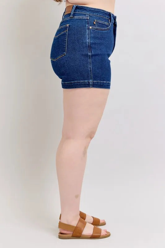 Dark blue denim shorts side close-up with front pocket, belt loops, and hem