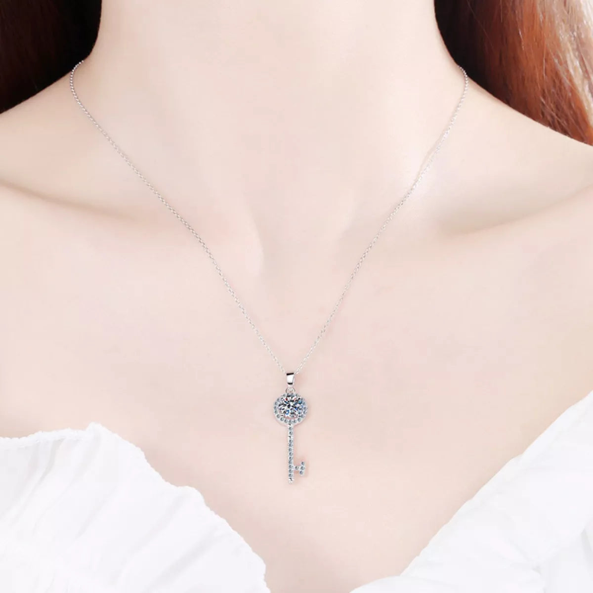 Sterling silver moissanite key pendant necklace worn on the neck; round stone with key drop