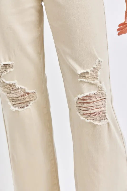 Close-up of bone jeans with frayed distressed knee patching