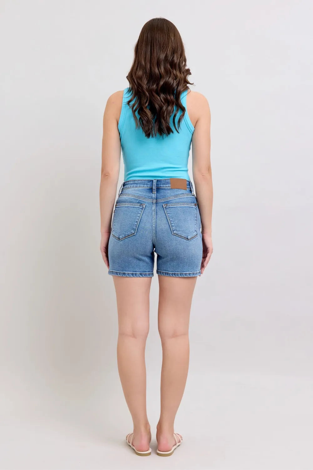 Medium wash denim shorts, back view from behind; belt loops and back pockets