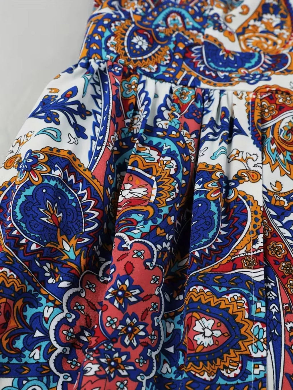 Paisley print fabric close-up in blue, cream, red, and teal