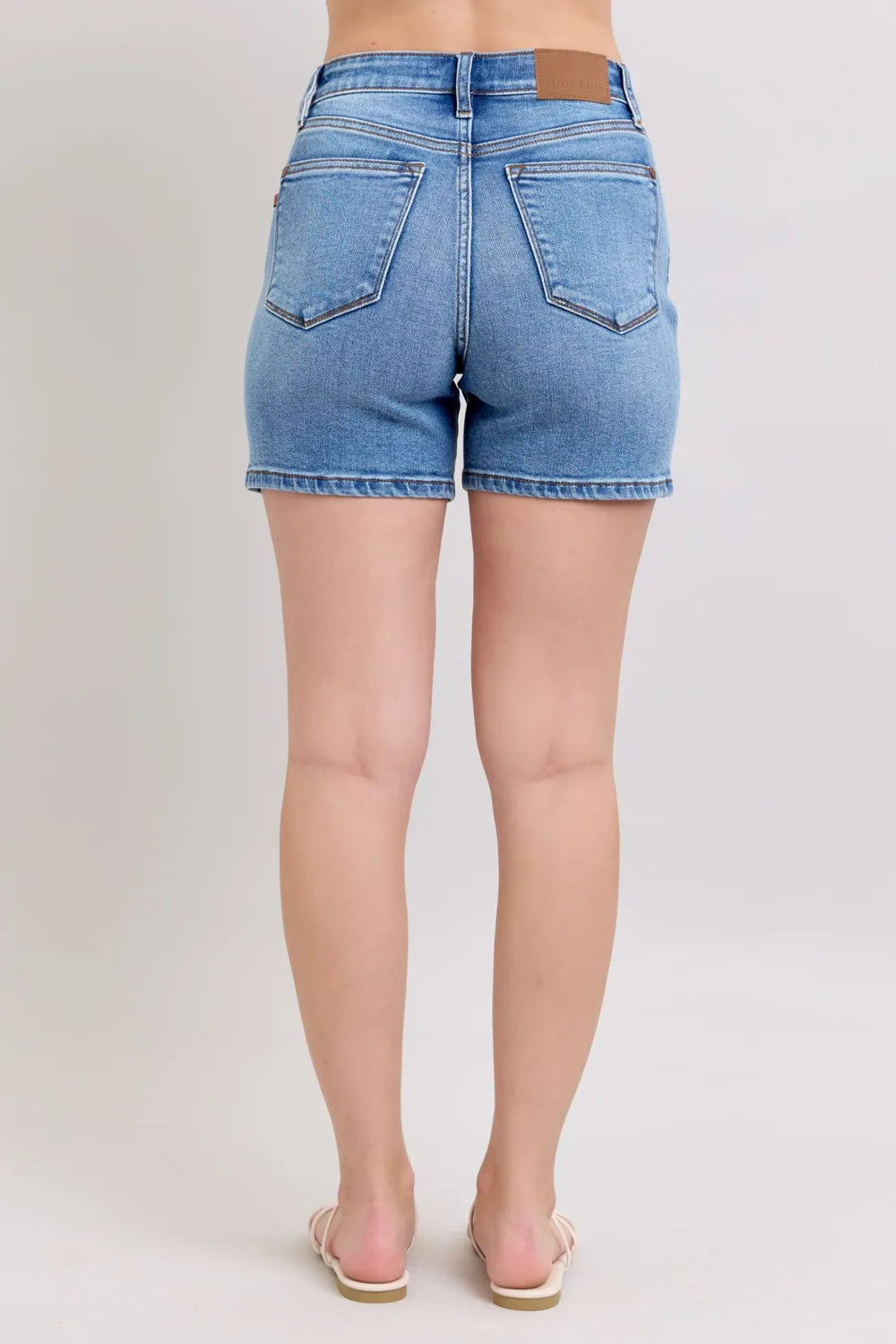 Back view of medium-wash denim shorts with two back pockets and short inseam