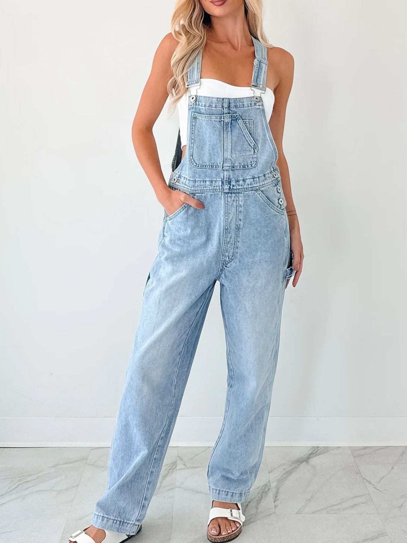 Light blue denim relaxed-fit overalls with wide straps and straight leg silhouette