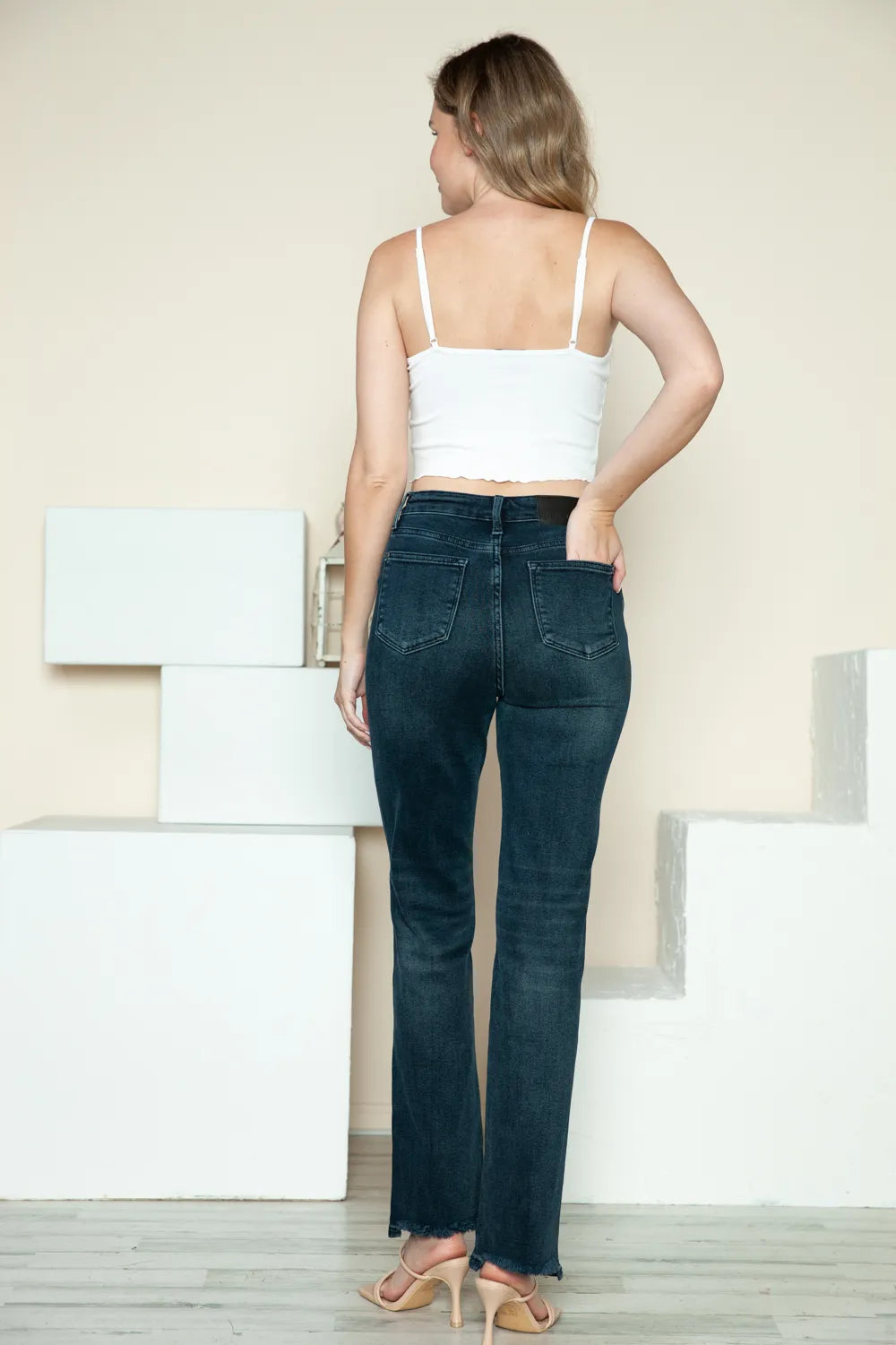 Dark blue straight jeans, button-fly front and raw hem, full-back view