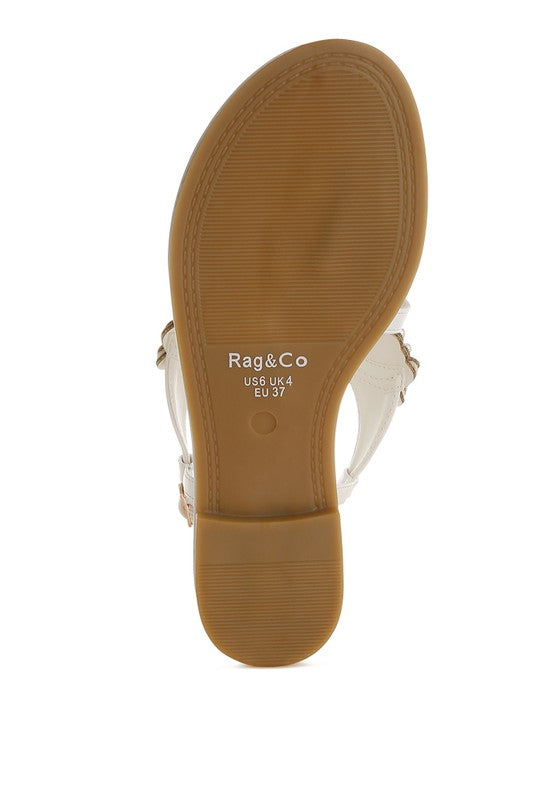 White flats with pin-buckle strap and pearl detail, flat sole view