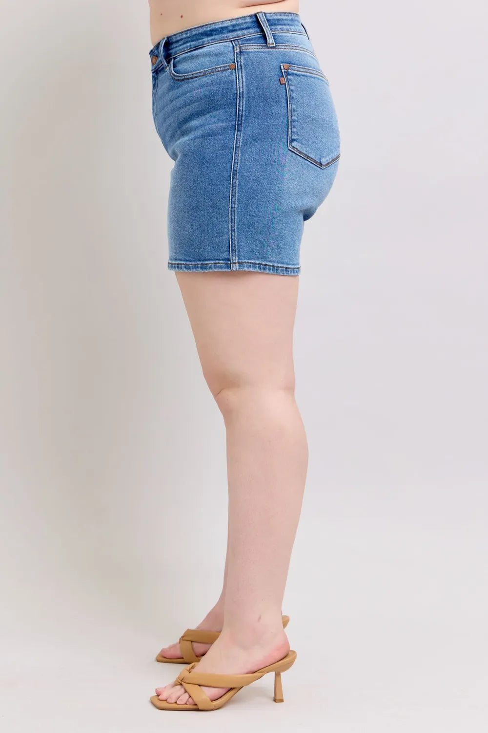 Medium wash denim shorts, side view; back pockets and 2-button front