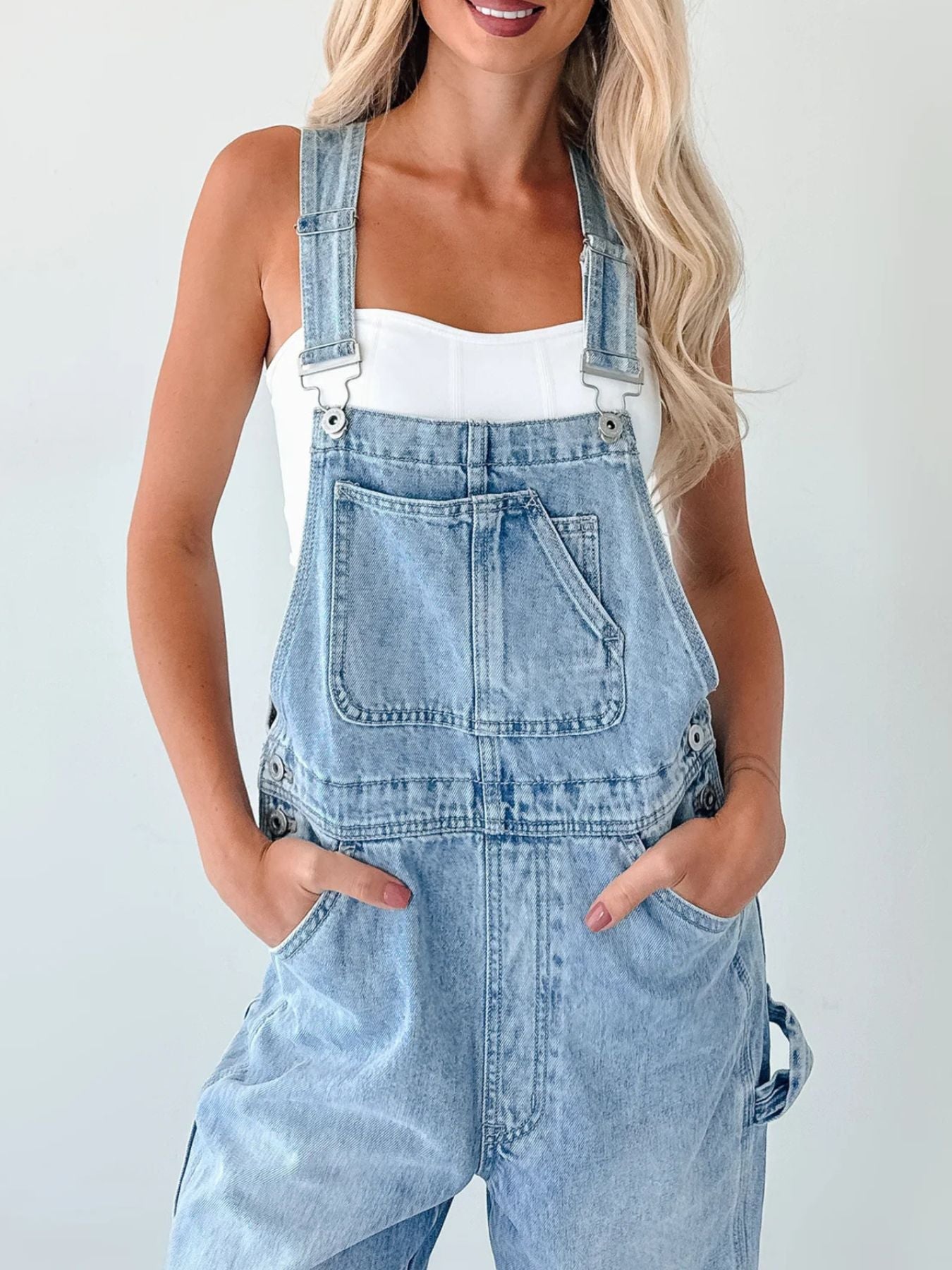 Light blue denim relaxed overalls with bib pocket, stitched seams and front side openings