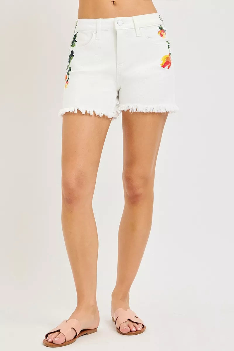 White high-rise denim shorts with colorful flower print and frayed hem