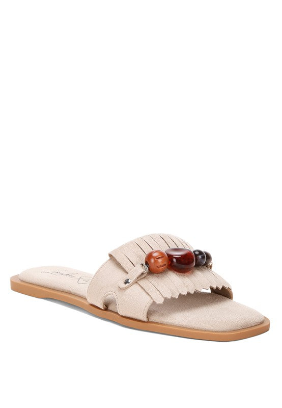 Beige microfiber slip-on flat sandal with bead cluster on front strap and fringe detail