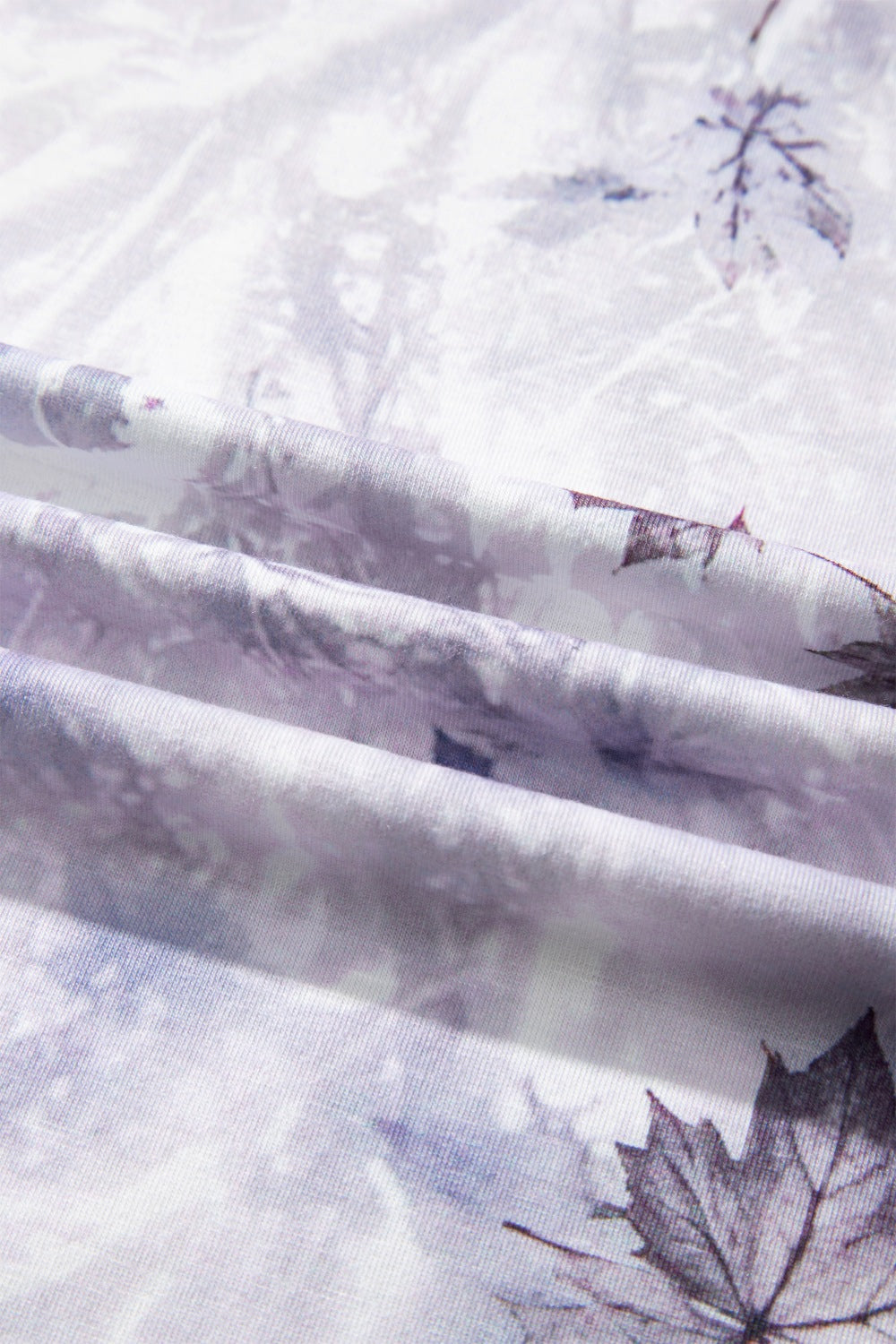 Close-up of light gray fabric with woodland camouflage leaf print and stitching lines