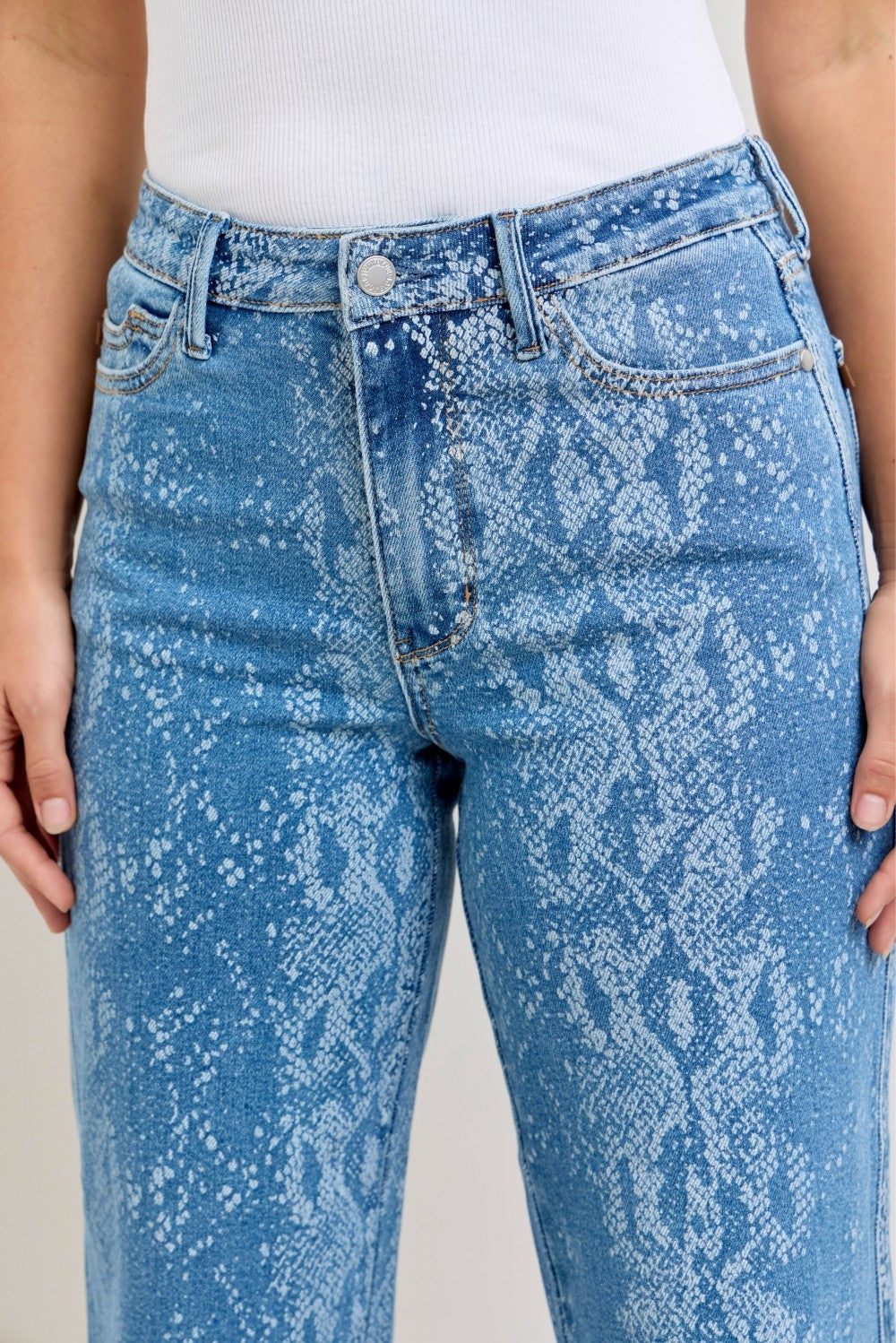 Front close-up: blue snake-print high-rise jeans, button waistband, belt loops.
