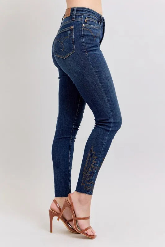Dark blue high-rise skinny jeans, side view with embroidered leg detailing