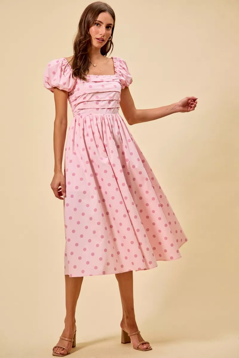 Pink cotton midi dress with polka-dot print, puff sleeves, and flowing gathered skirt