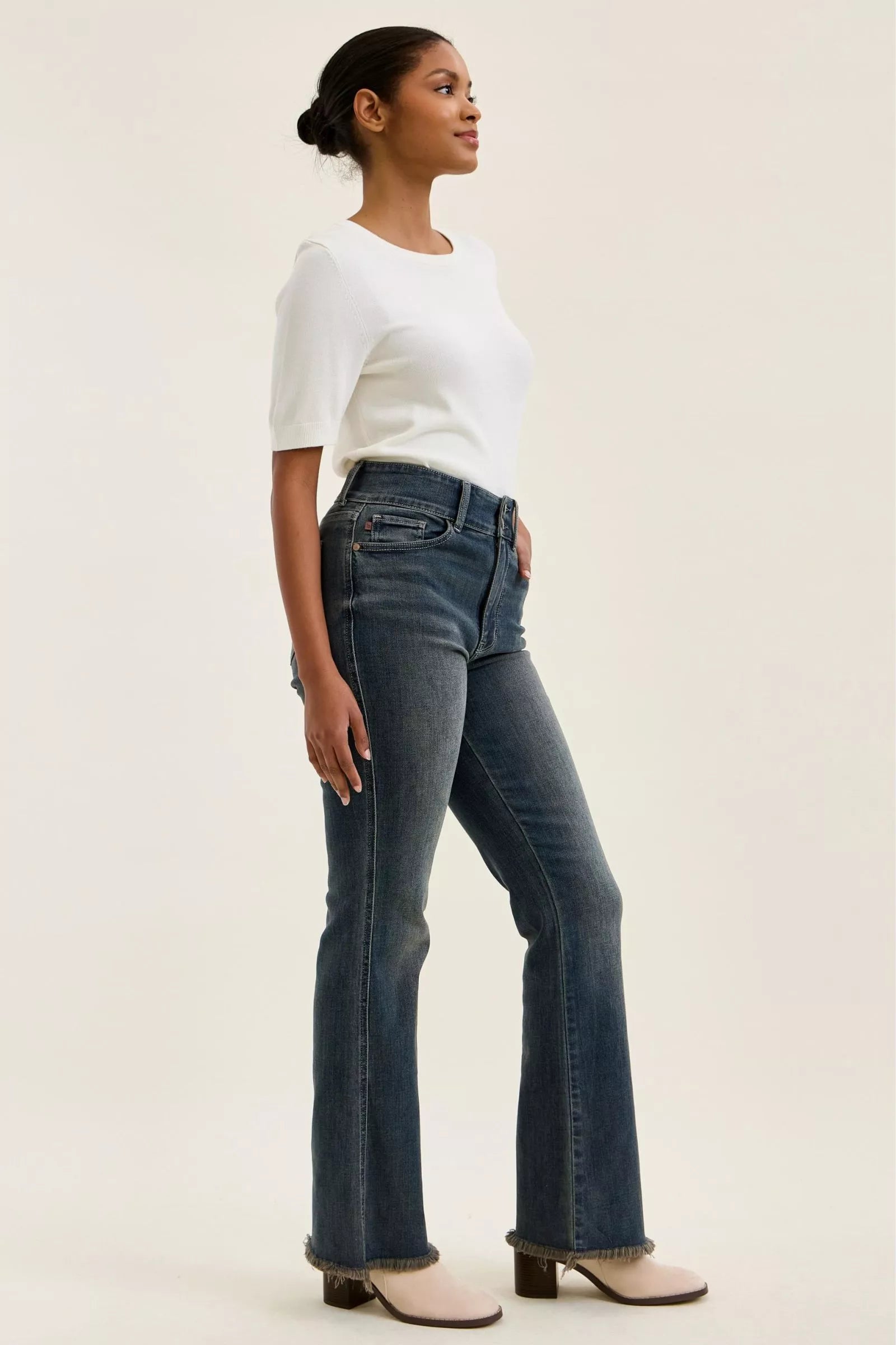 Side profile medium-wash high-waist jeans with frayed cuffs and double-button waist