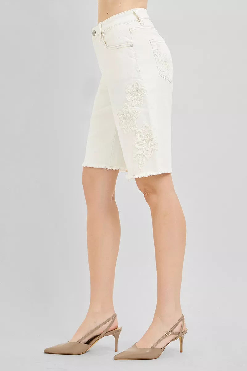 Side view: cream denim bermuda shorts with floral embroidery and frayed cuffs