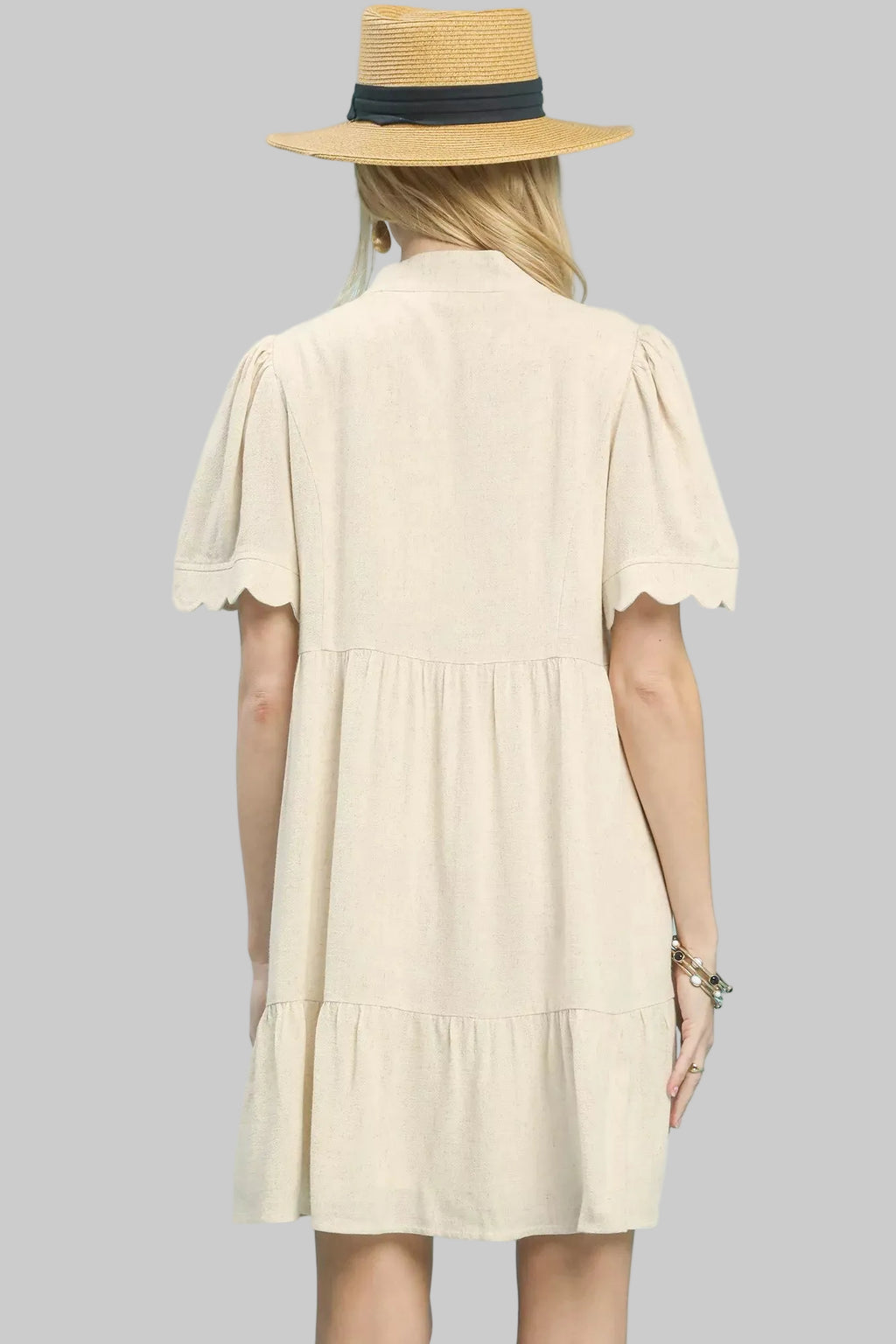 Back view: oatmeal linen babydoll dress with tiered layers and scalloped sleeves
