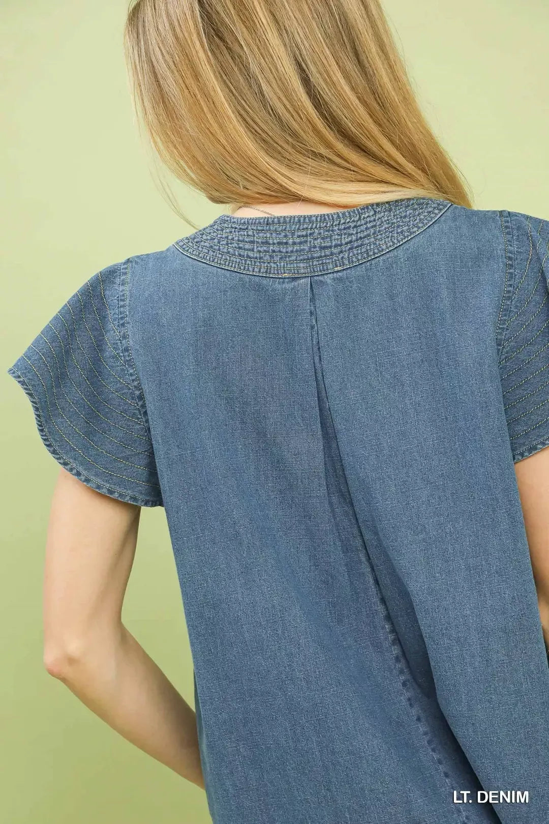Back view of light denim cap-sleeve top with vertical seam and yoke stitching