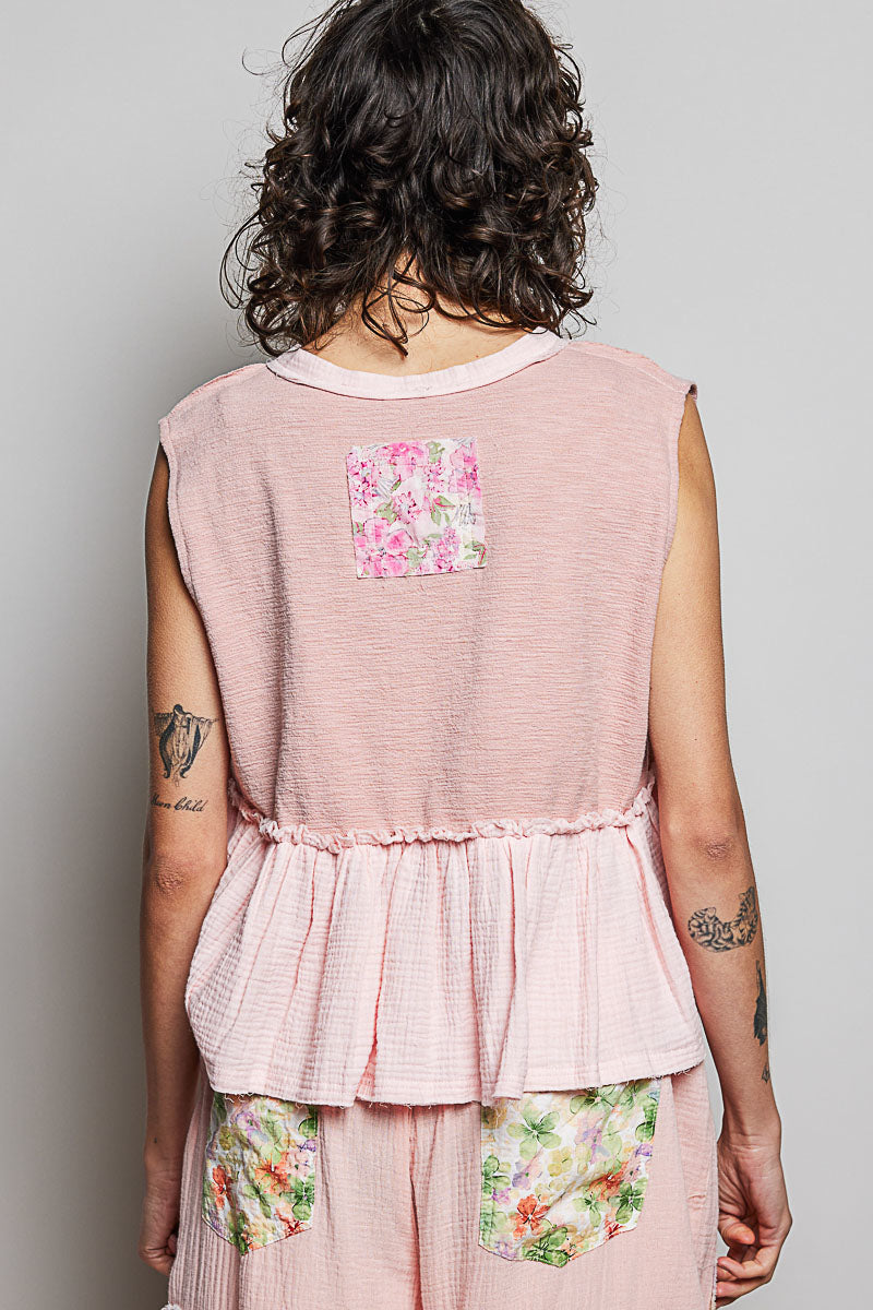 Back view: powder pink sleeveless top with floral patch and gathered ruffle waist