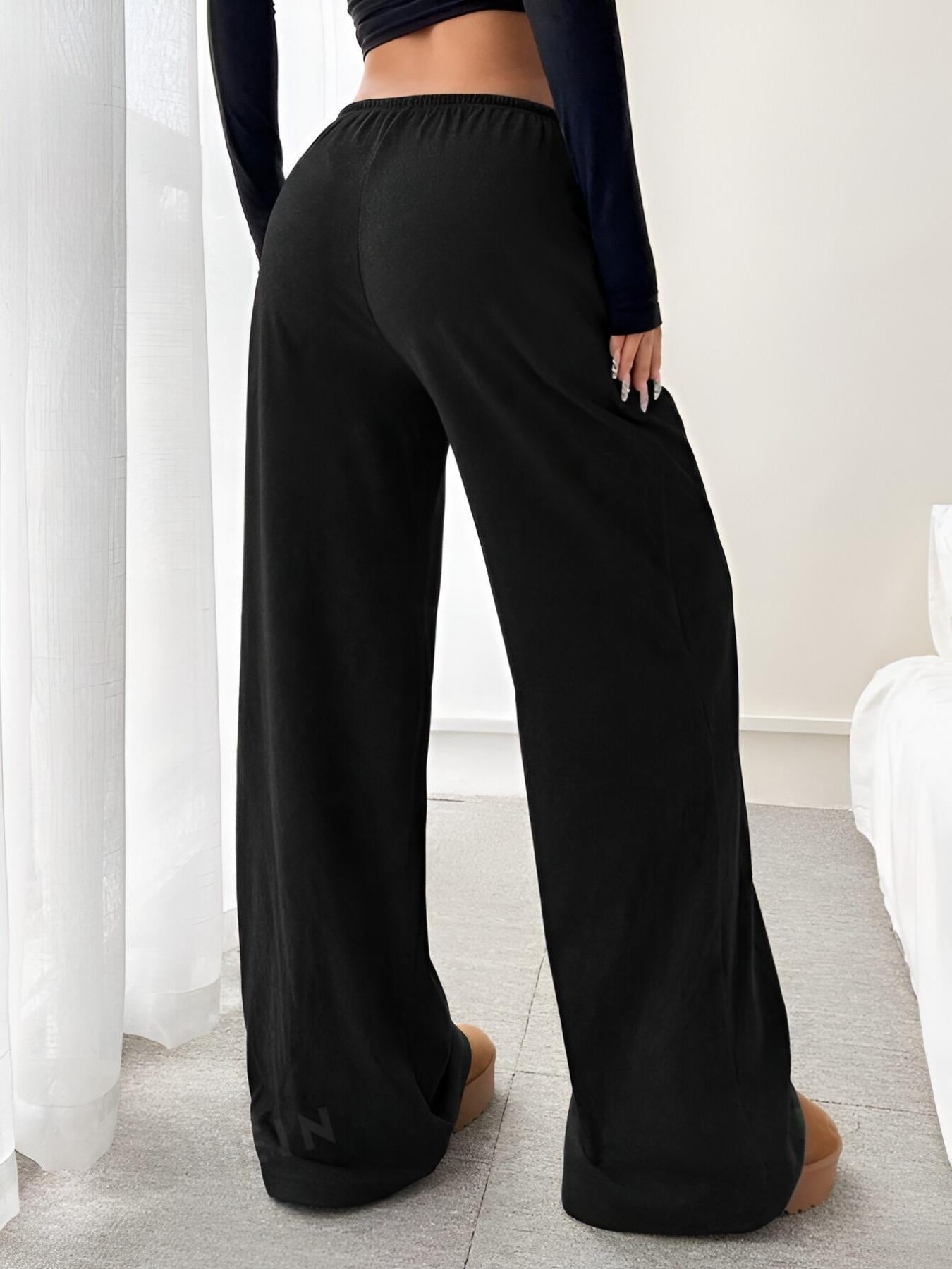 Black relaxed fit drawstring pants, back view with wide legs and elastic waist