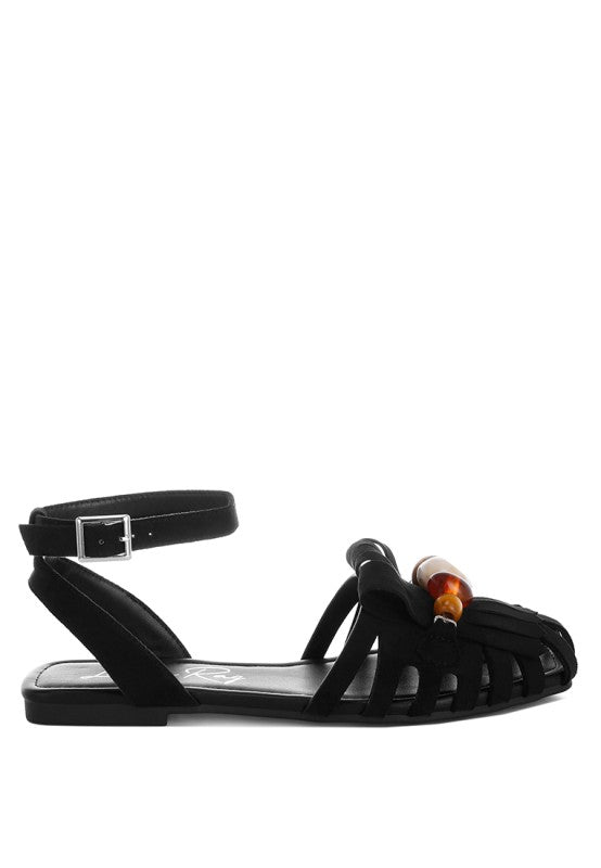 Black microfiber flat sandals with adjustable ankle buckle strap and fringe beads