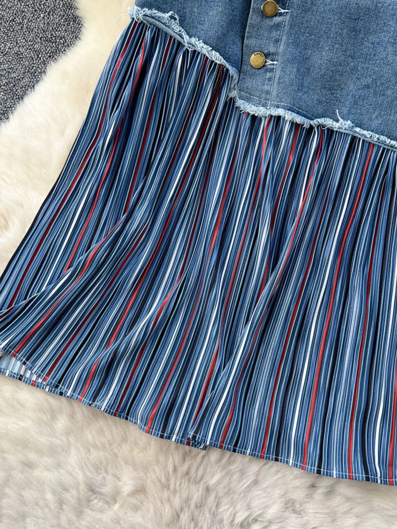 Detalle de la falda: franja inferior a rayas verticales multicolor con dobladillo deshilachado