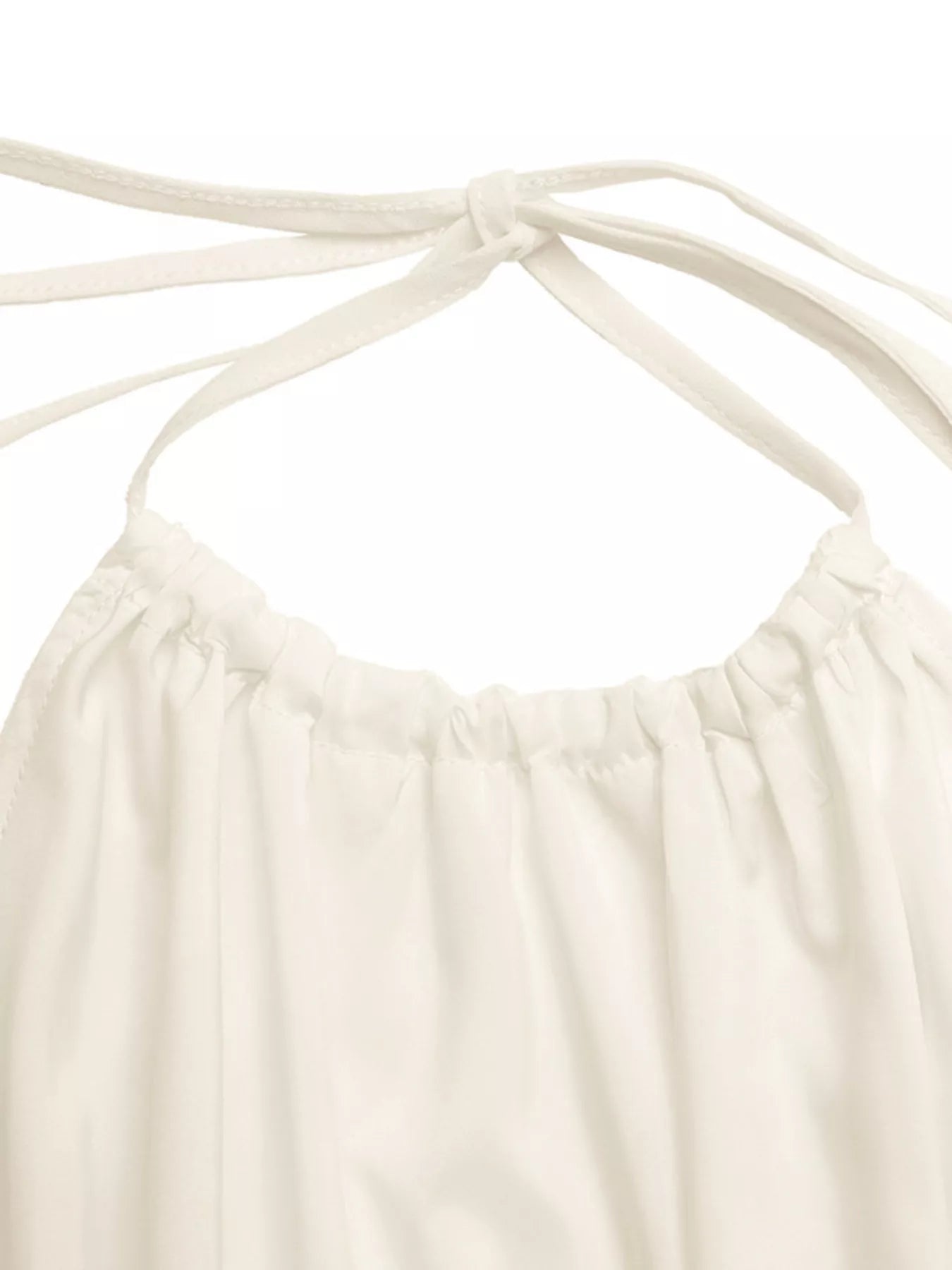 Close-up: white halter neckline with bow-tie straps and gathered ruffle edge