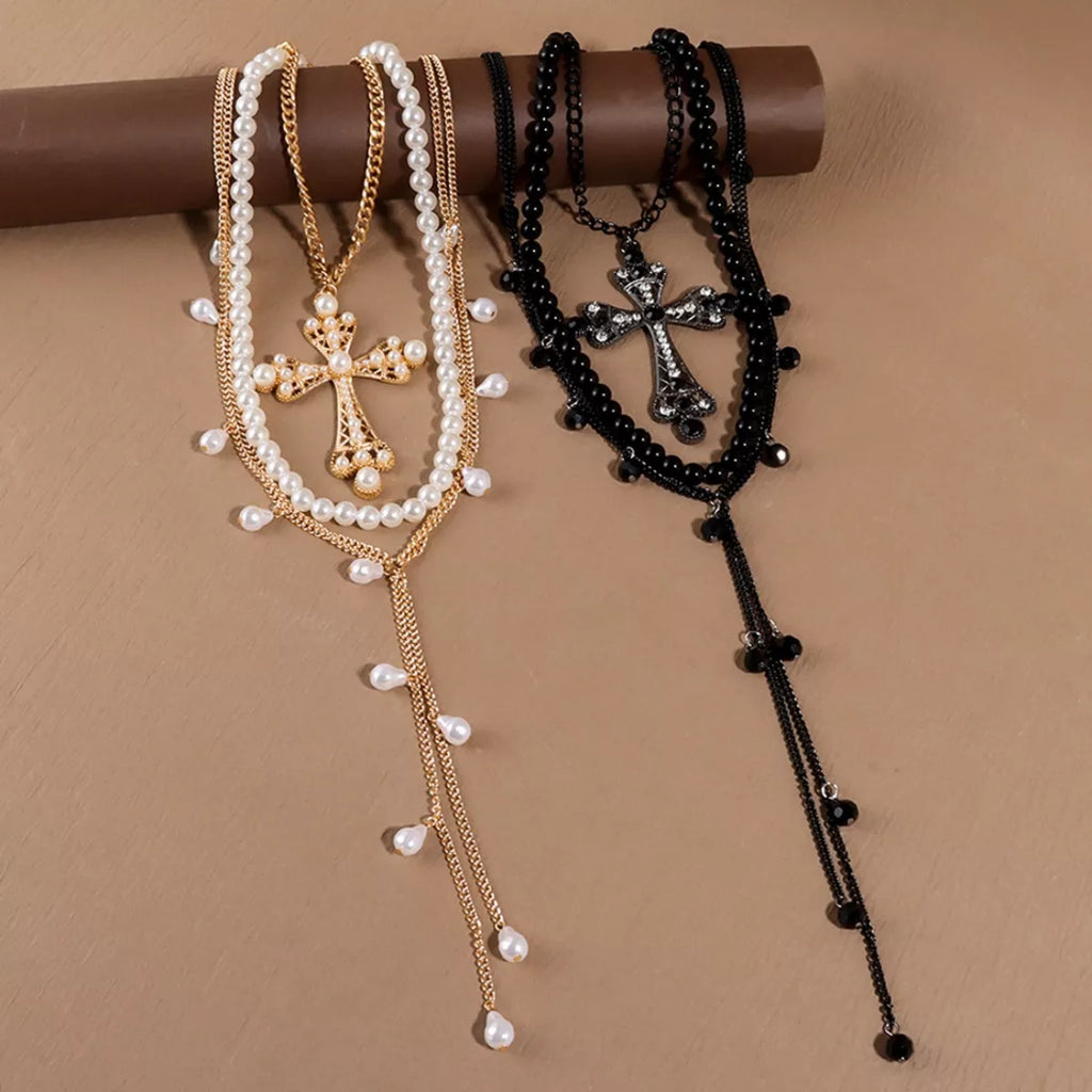 Pearl cross pendant necklace set with layered white pearls, gold-tone, and black bead chains