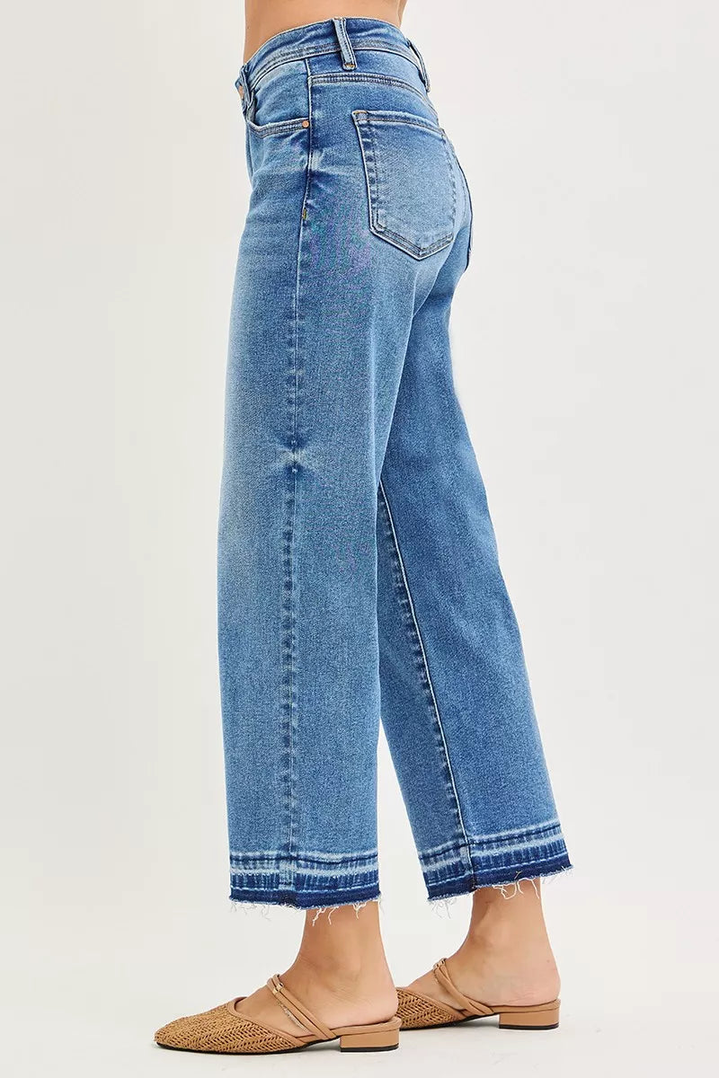 Medium-wash cropped boyfriend jeans from side view; scoop pocket and raw hem edge