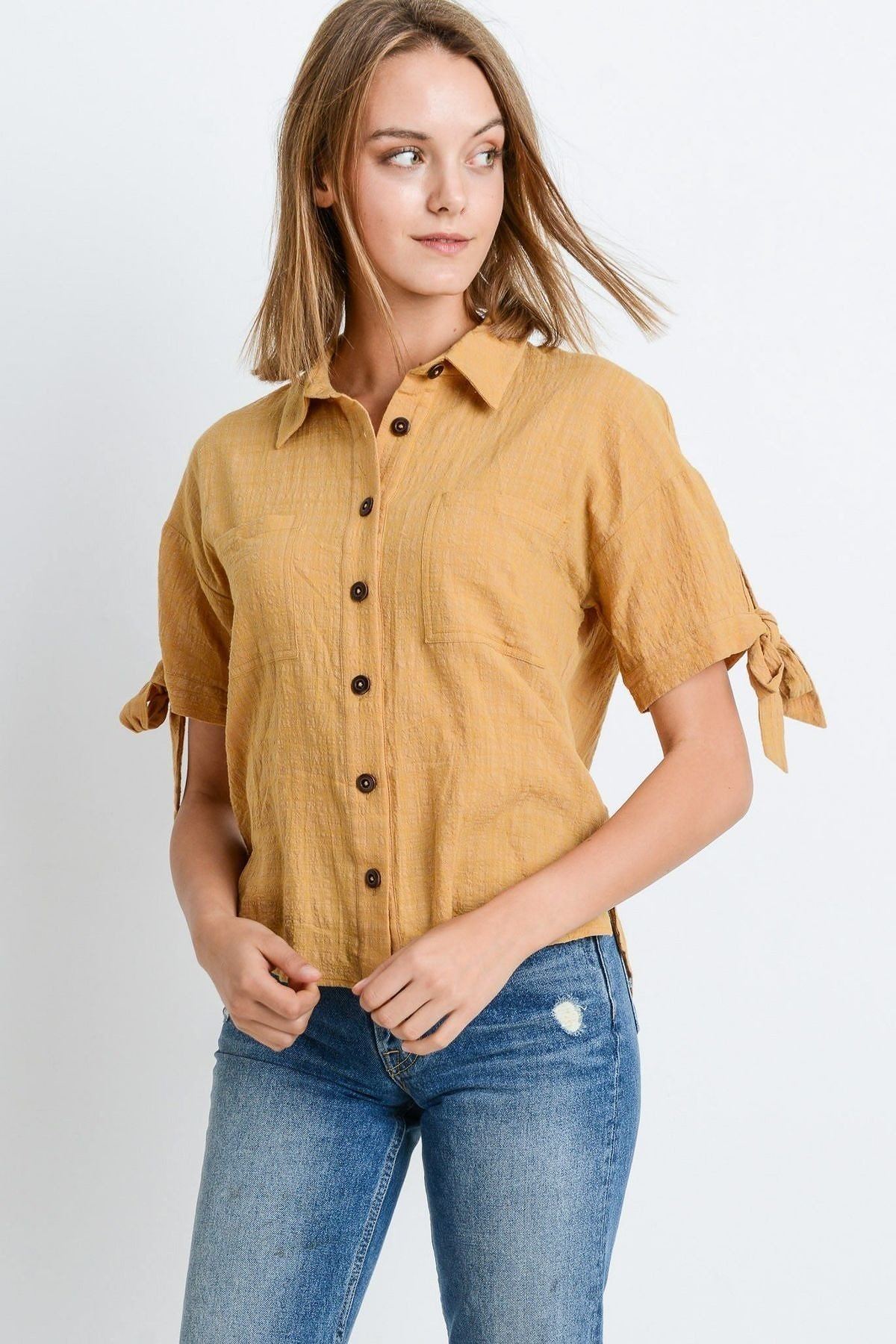Tan short-sleeve button-up top with tie sleeves and chest pocket