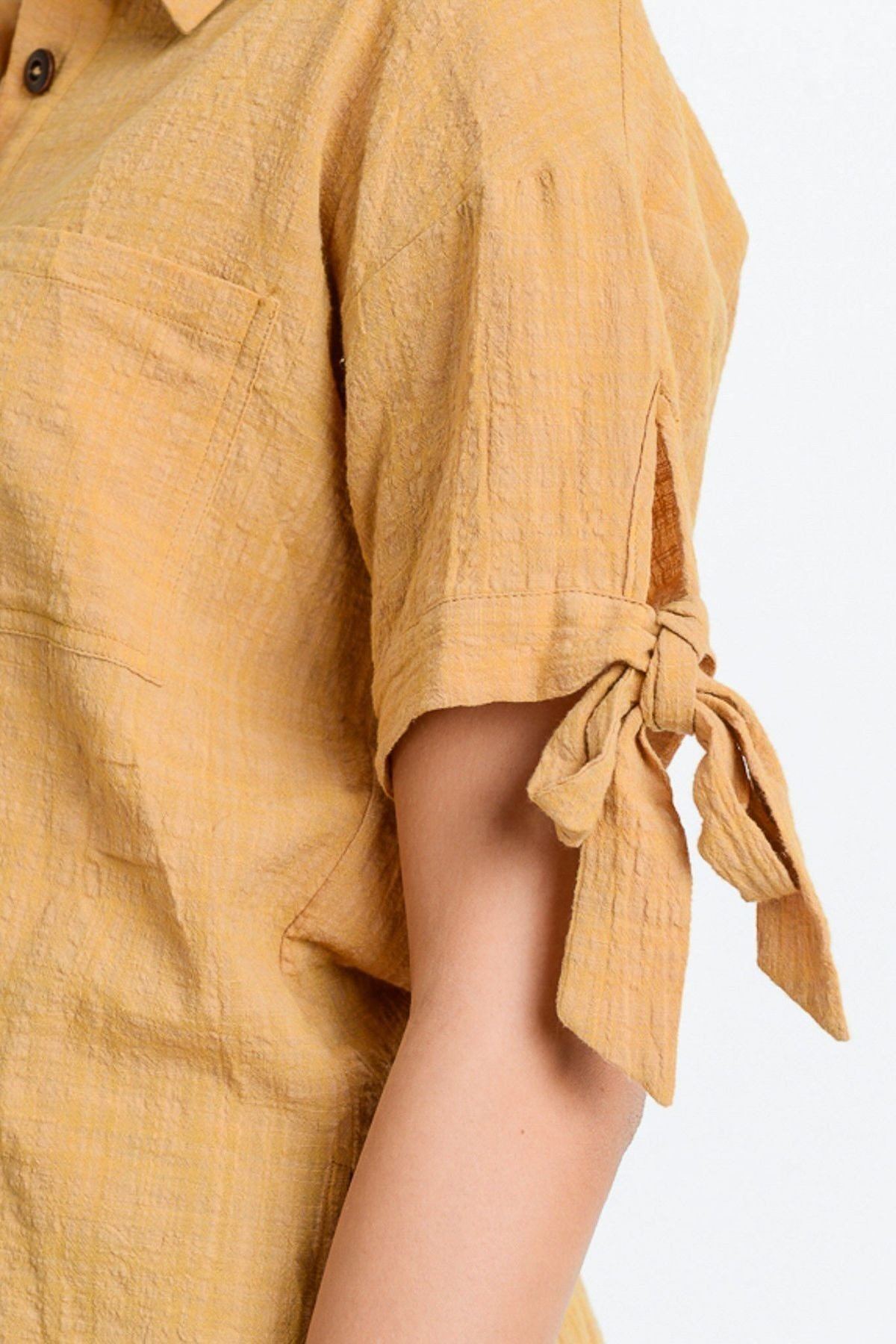 Close-up: tan tied sleeve cuff on short-sleeve button-up top