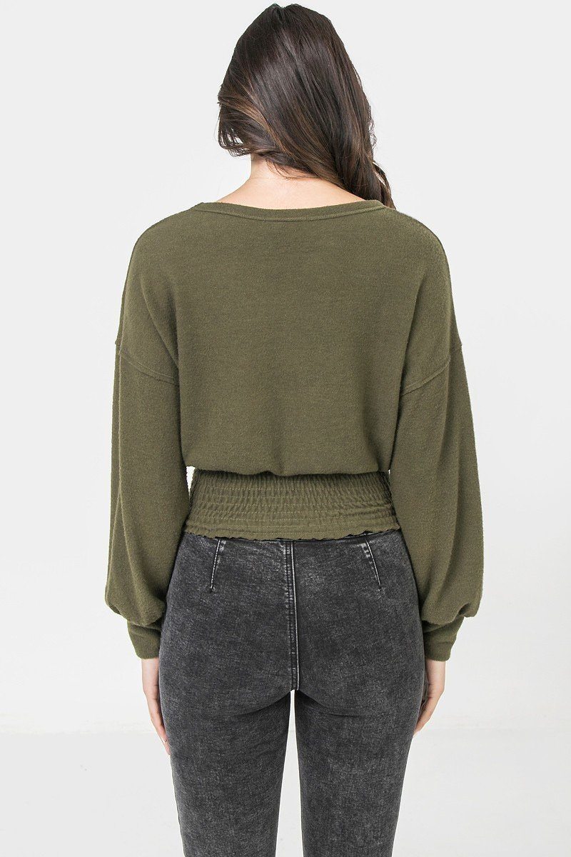 Olive knit top from the back view with wide neckline and smocked waist hem
