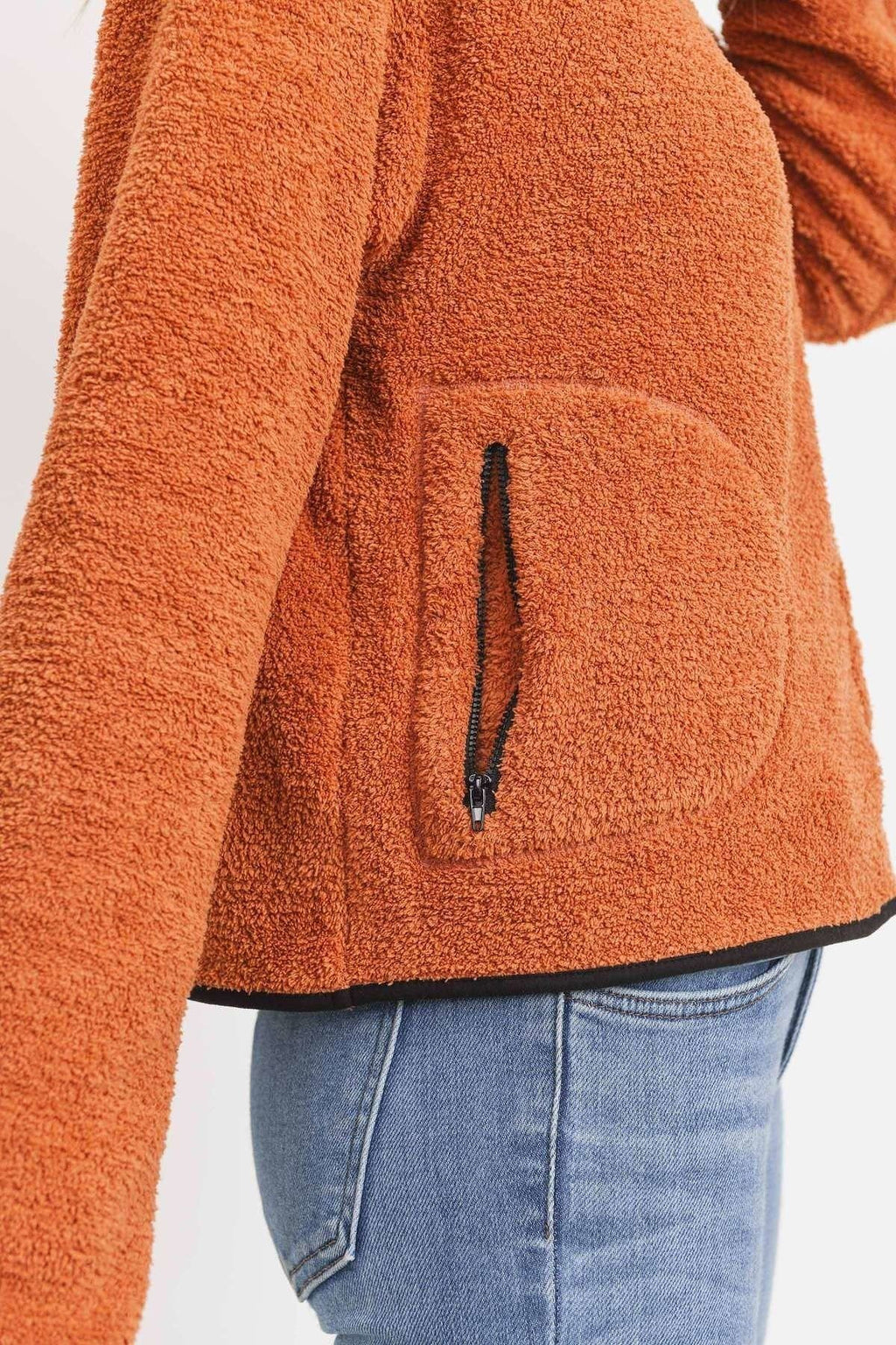 Close-up: orange terry half-zip pullover with black zipper and front pocket