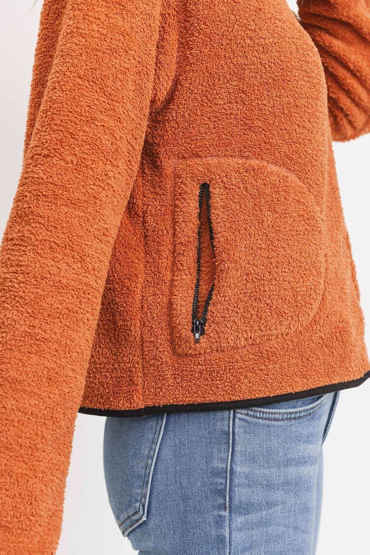 Close-up: orange terry half-zip pullover with black zipper and front pocket