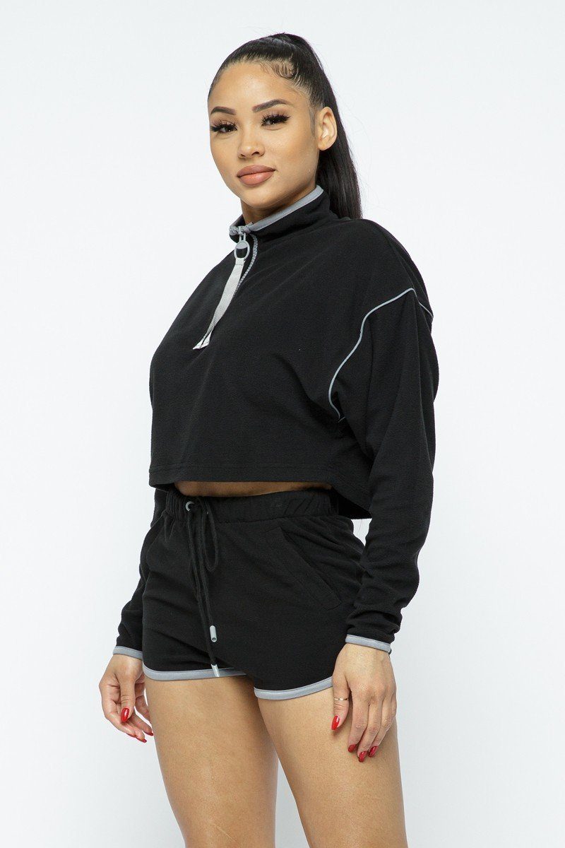 Black crop top with quarter-zip and contrast piping, tied high-waist shorts