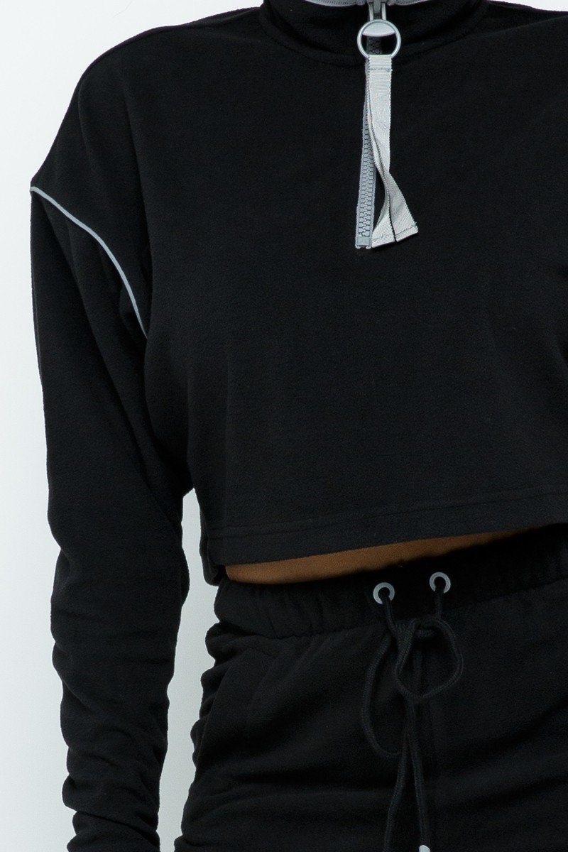 Black long-sleeve crop top with half-zip ring pull and contrast piping on seams