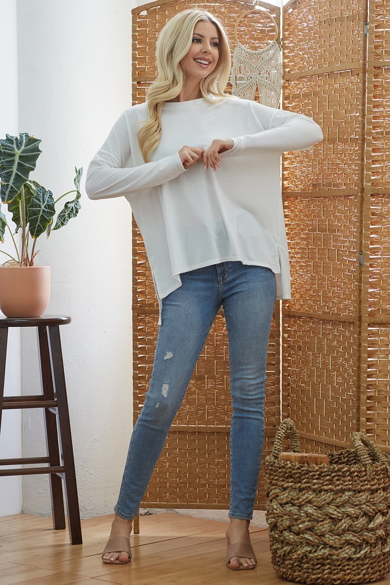 White long-sleeve top with curved hem and loose, draped silhouette