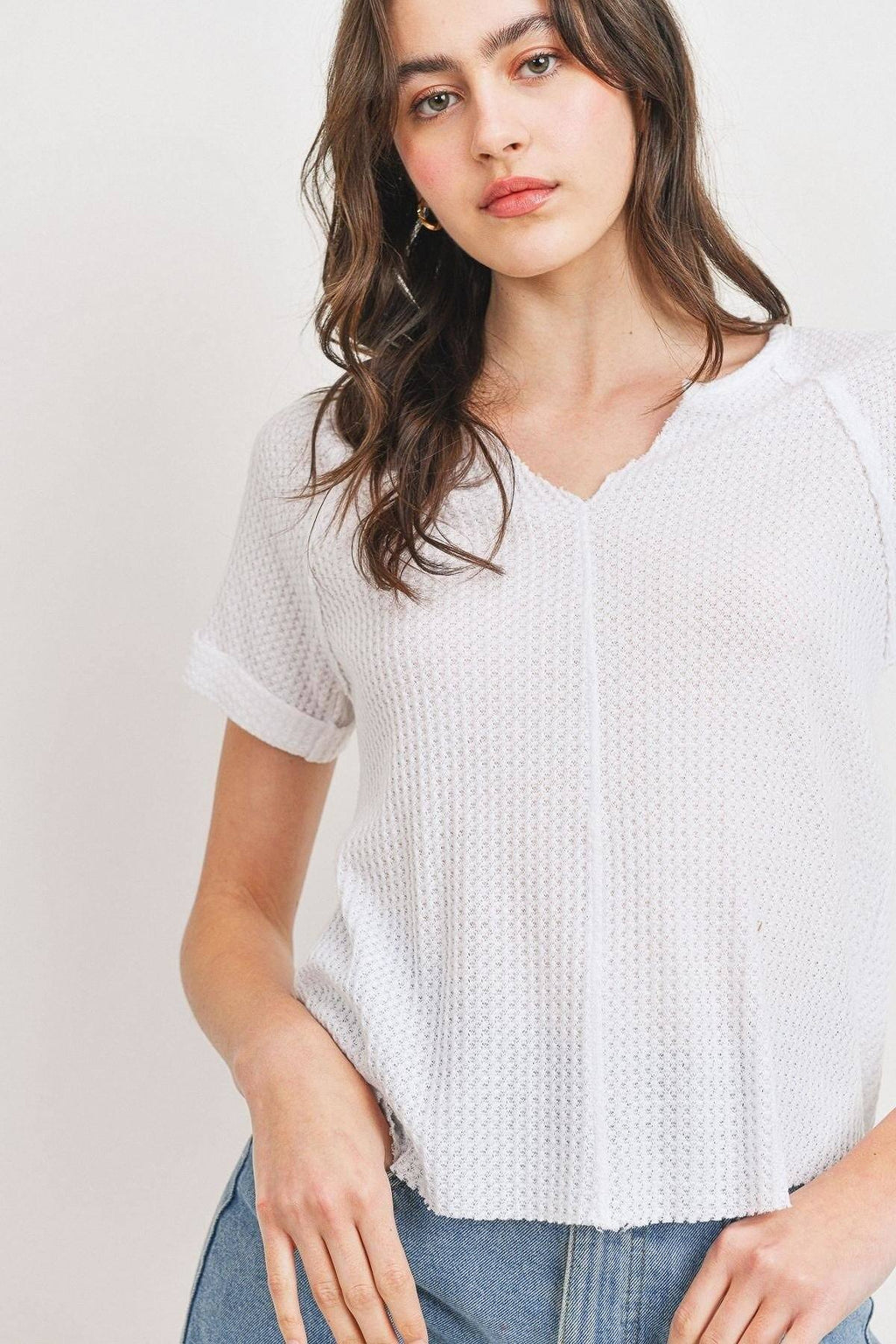 White waffle V-neck top with vertical seam detailing and rolled short sleeves