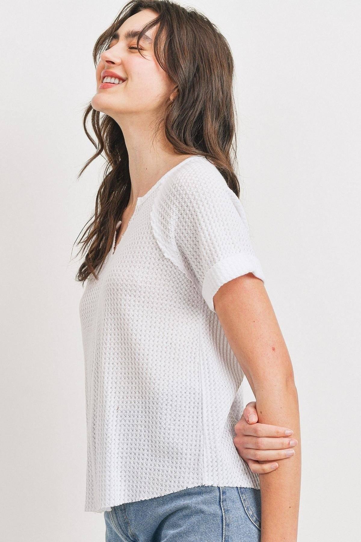 Side view: white waffle V-neck short-sleeve top with raw-edge hem and rolled cuffs