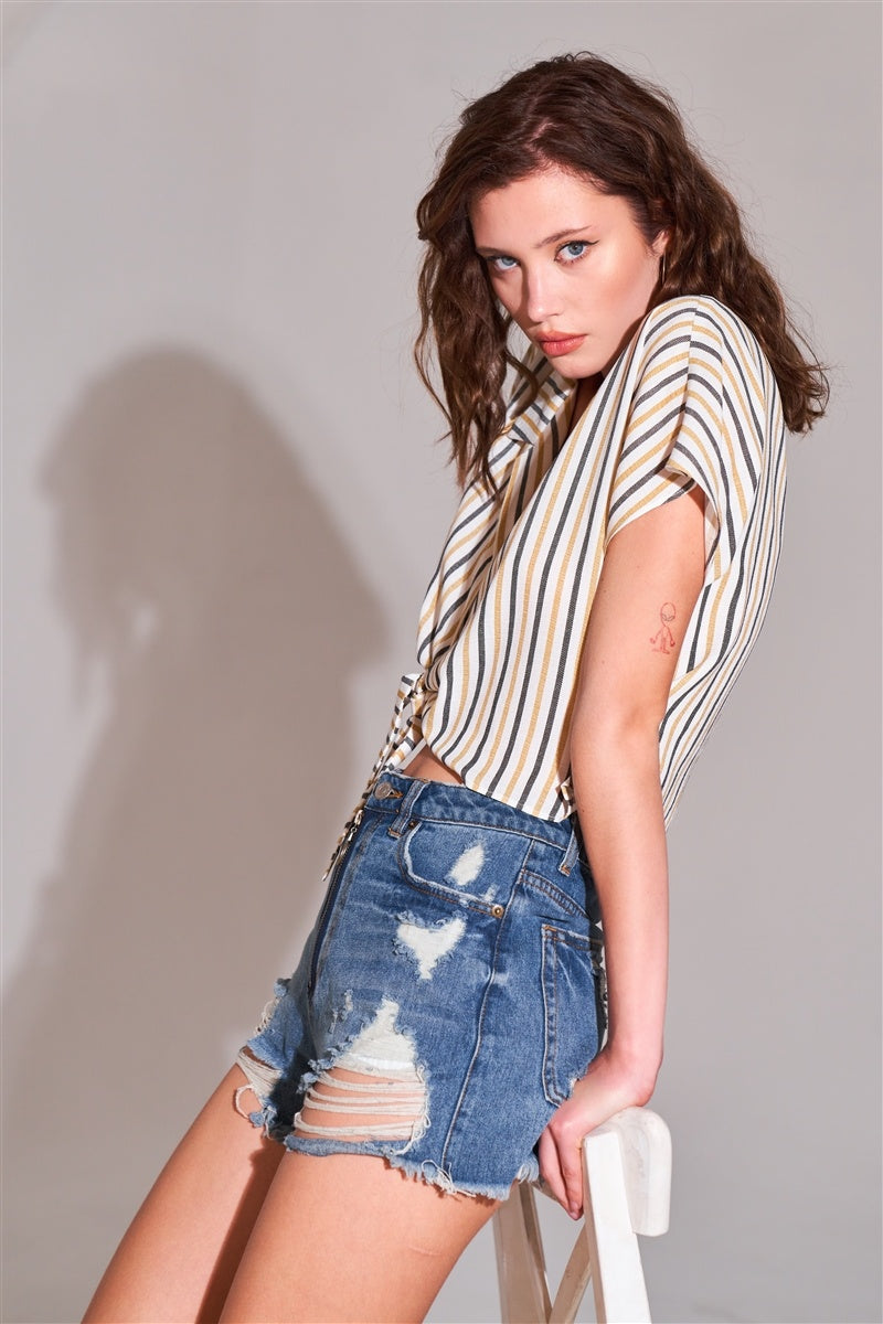Medium-wash denim high-waist mini shorts with ripped panels, front zip, frayed hem