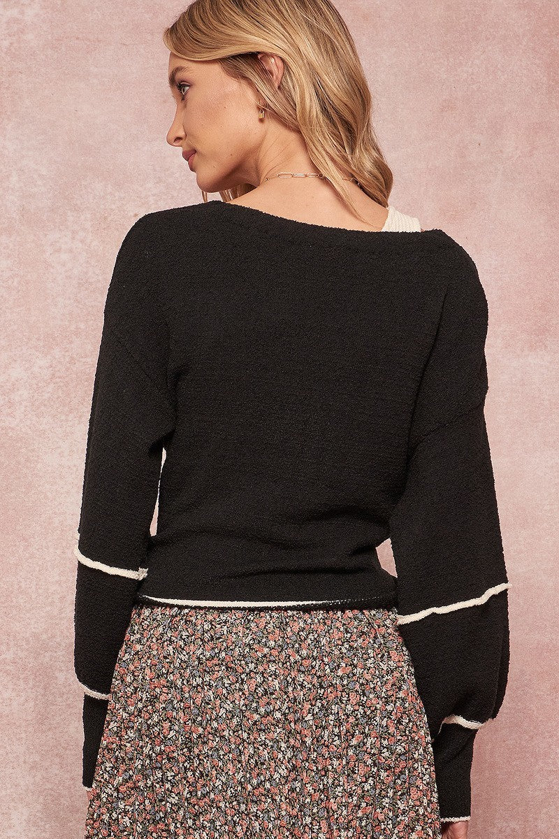 Black cardigan back view with contrast white sleeve trim and tied waist detail.