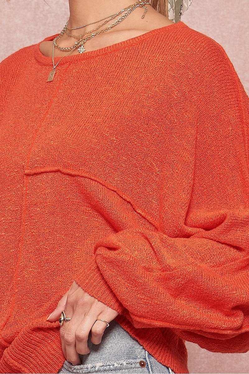 Orange knit sweater close-up: textured stitches and ribbed cuff sleeve