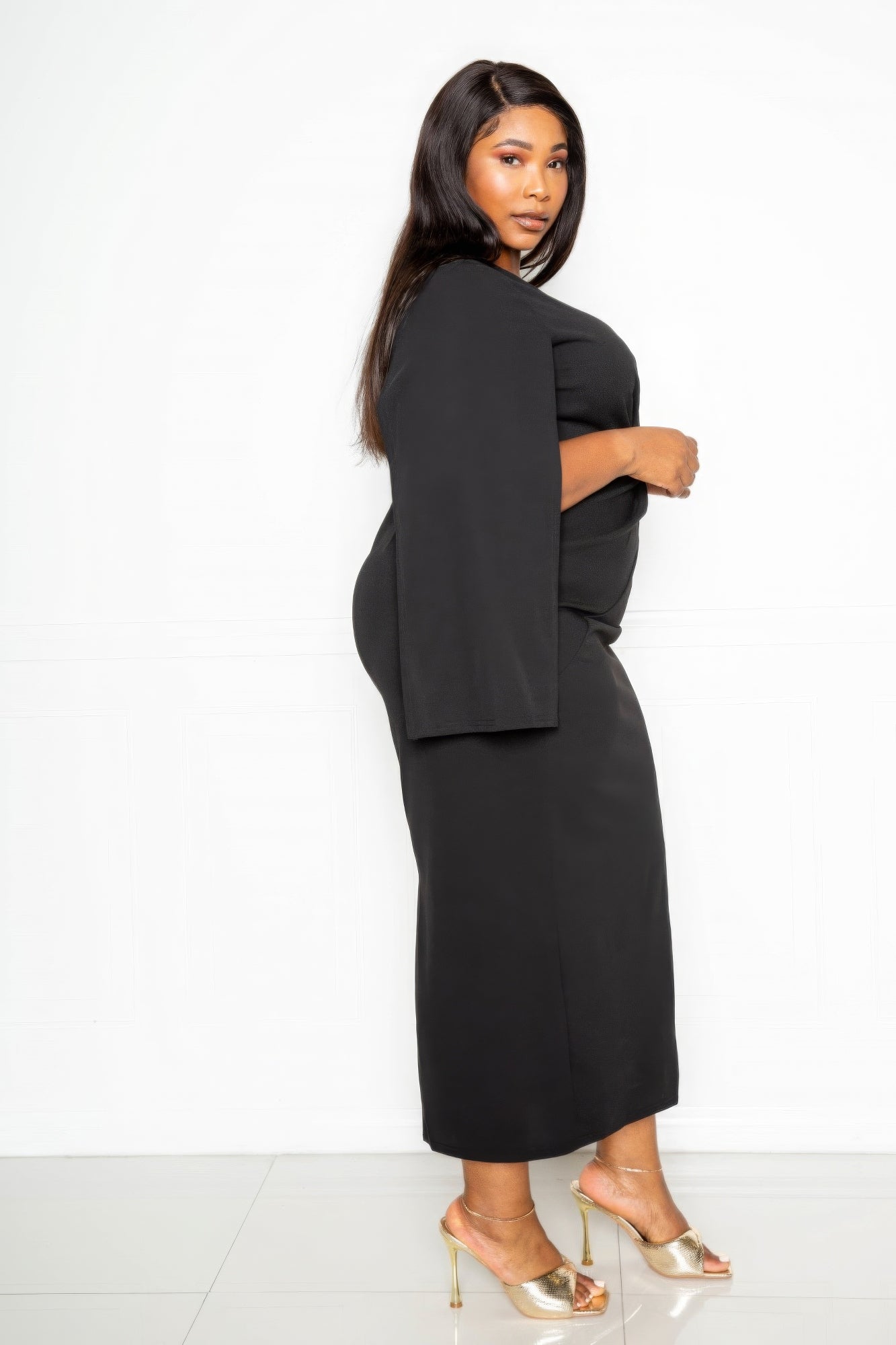 Side view of cape-sleeve dress with knot detail, black midi length