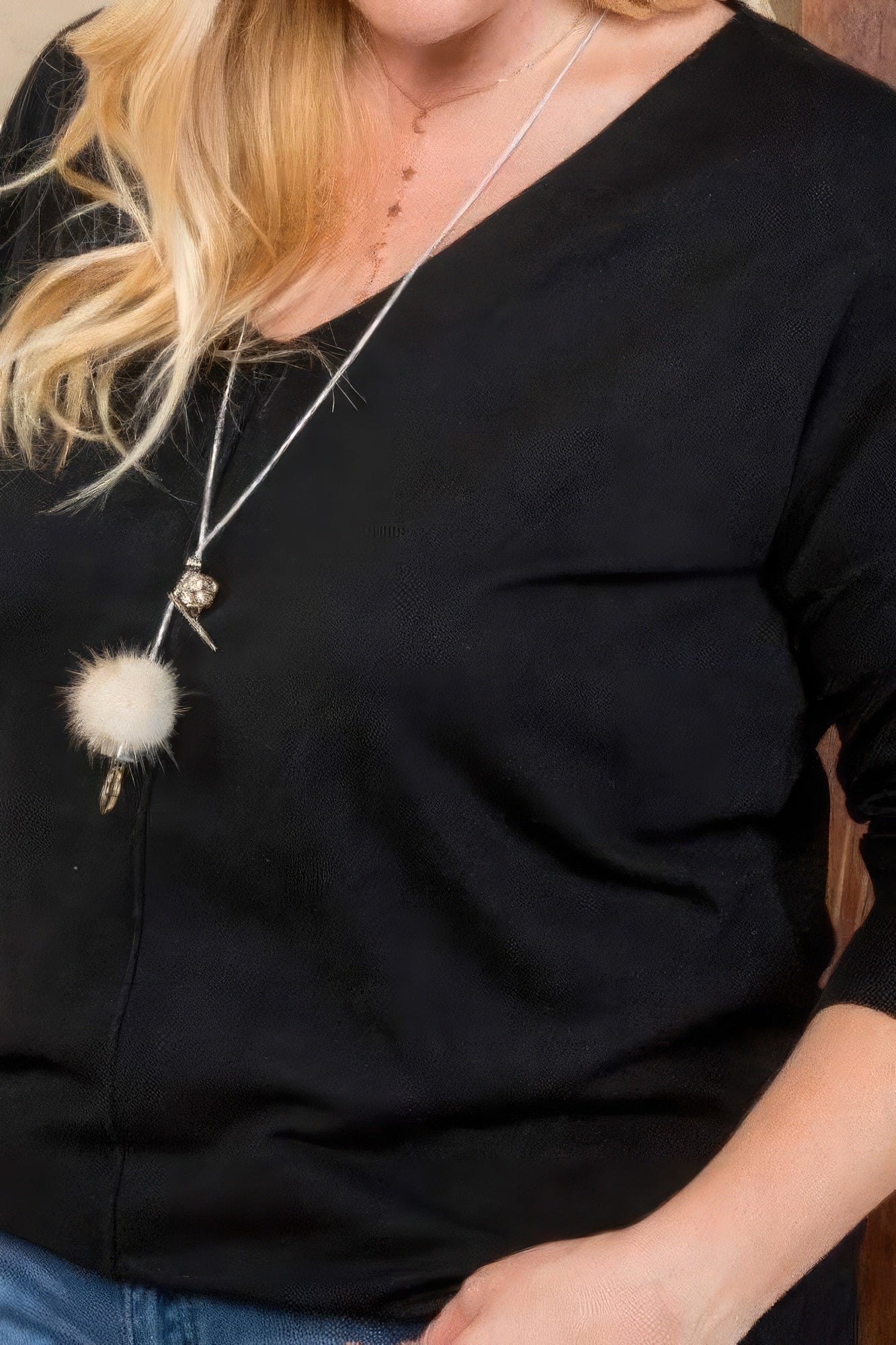 Close-up of black V-neck sweater with 3/4 sleeves and hi-lo side seam slit