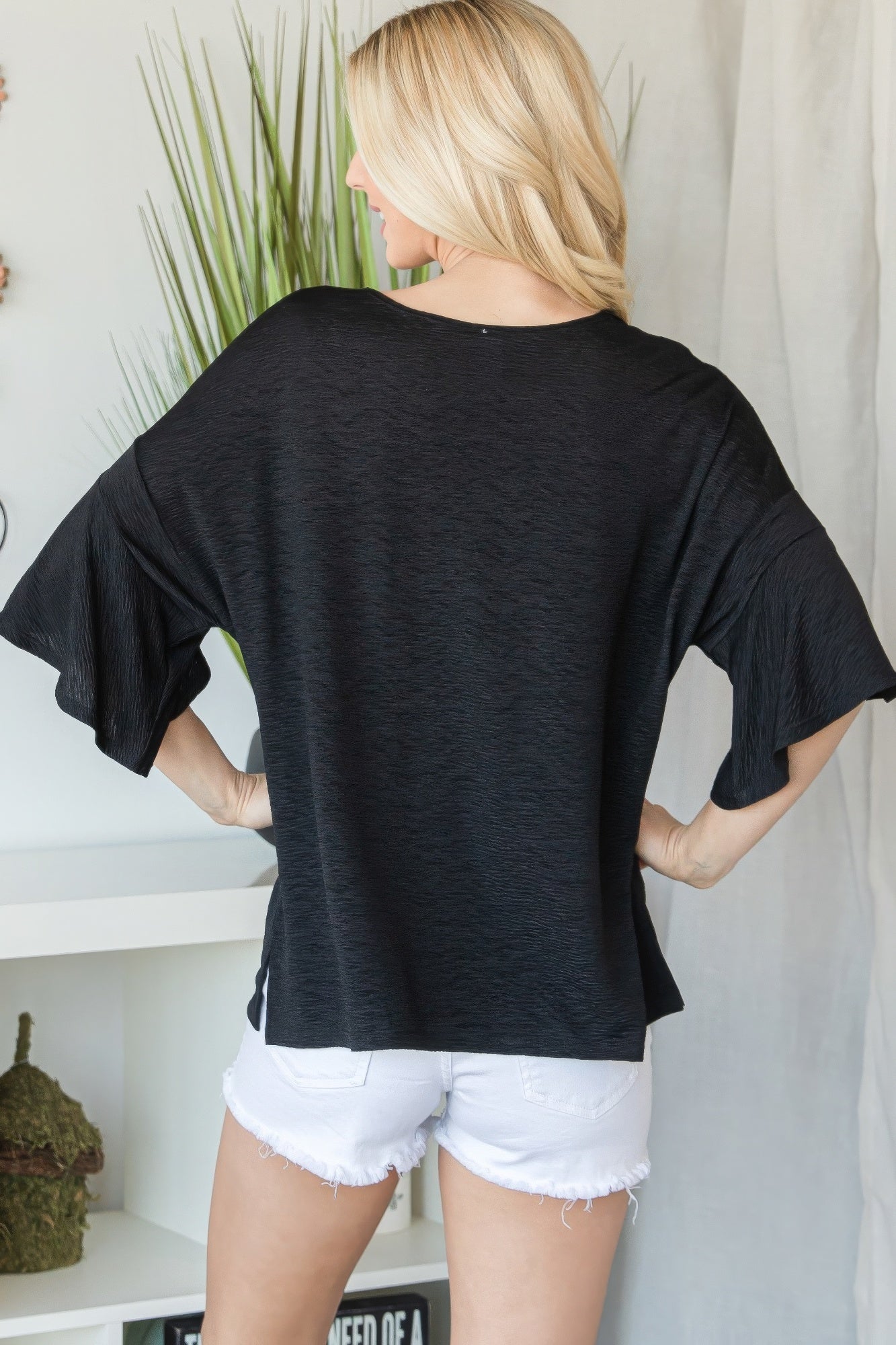 Back view: flared short-sleeve black top with curved hem