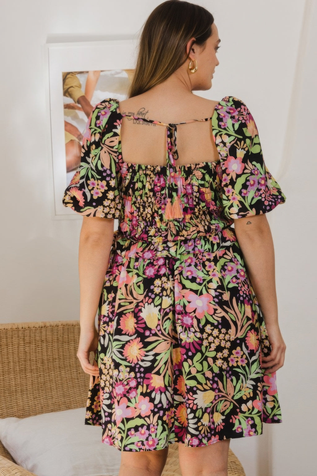 Back view of floral printed mini dress with tie-back opening and smocked waist