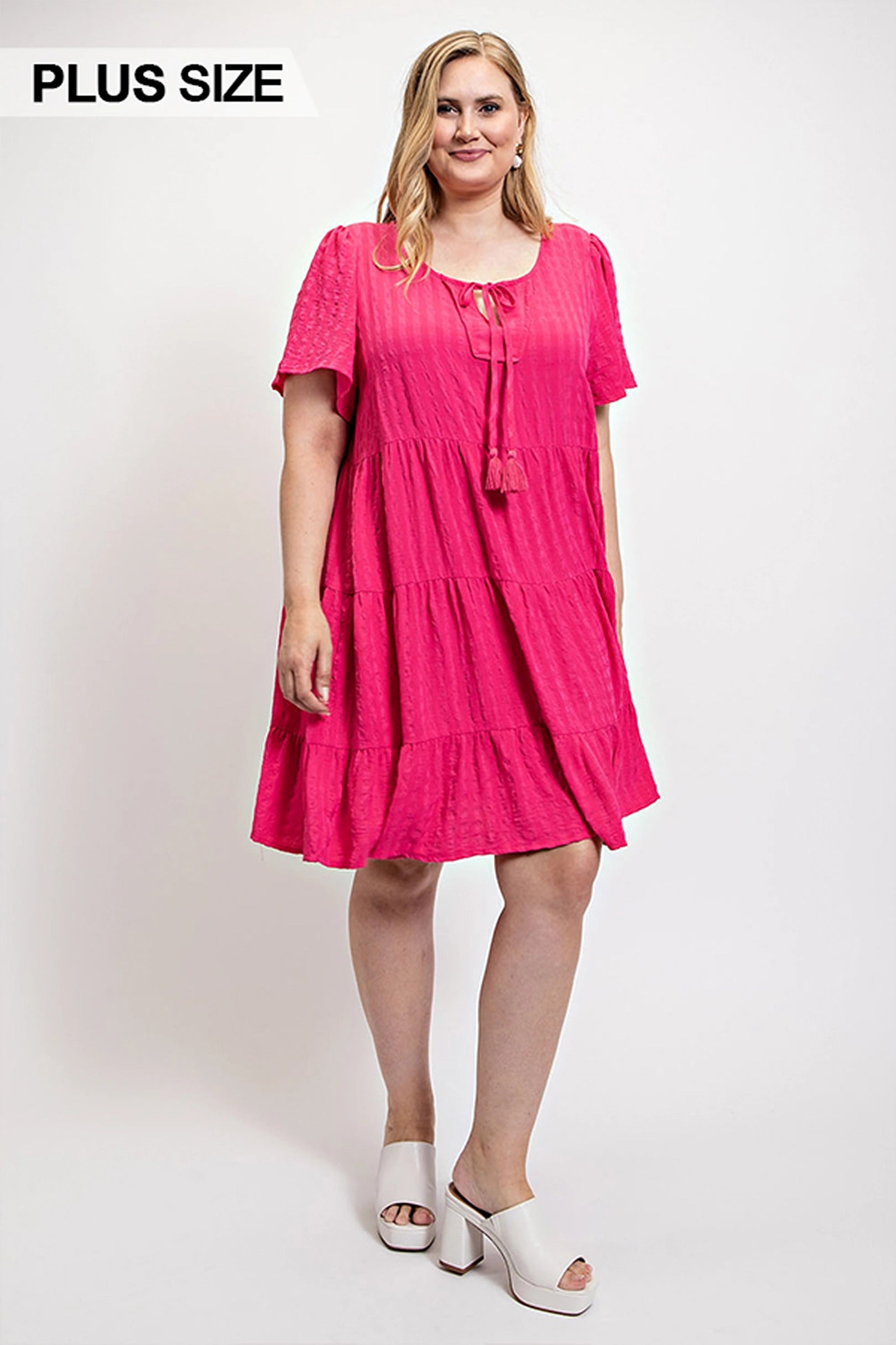 Textured fuchsia tiered swing dress with tassel tie at neckline, short sleeves
