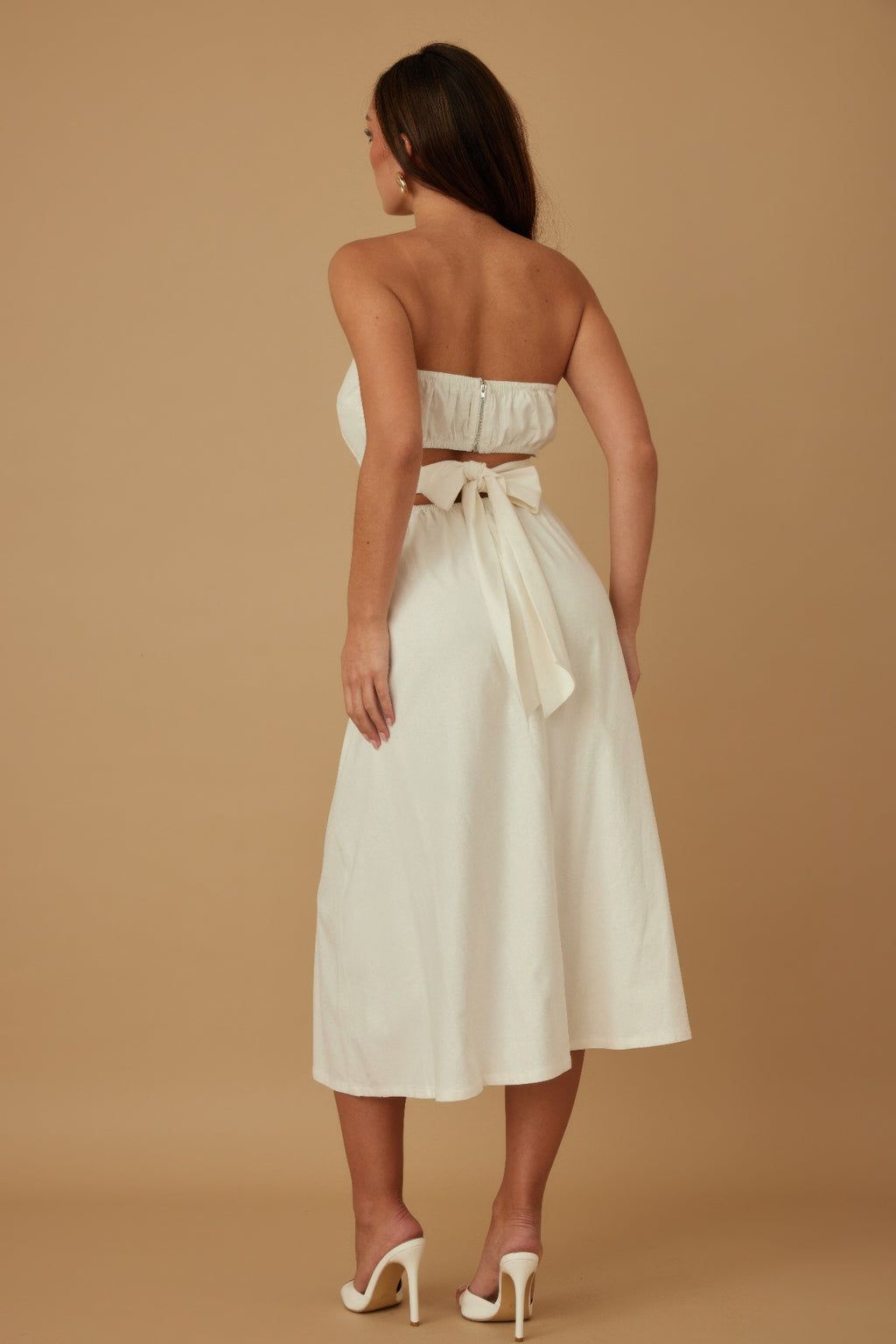 Back of ivory strapless linen dress with waist tie and midi skirt silhouette